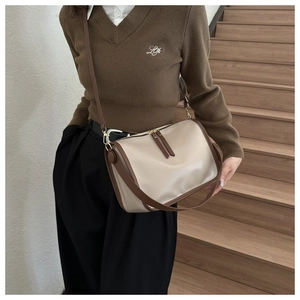 Detail of minimalist beige tote bag with brown straps and golden zippers worn by model