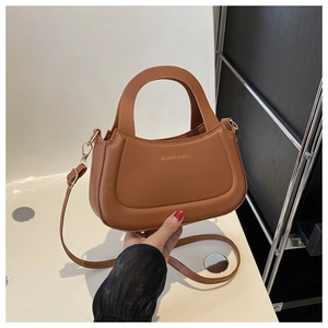 Close-up of caramel retro crossbody bag with round handle and gold FASHION & BAGS logo