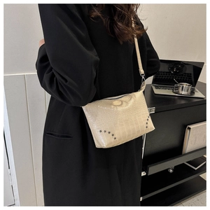 Detail der beigefarbenen Schultertasche aus Krokolederimitat mit Nieten und Reißverschluss