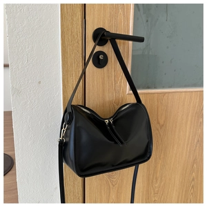 Detail of minimalist black crescent moon shoulder bag with smooth matte PU leather texture