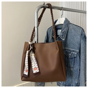 Brown tote bag detail with woven handle and patterned silk scarf in a lifestyle setting
