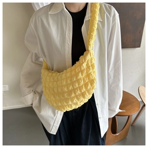 Detail of bright yellow pleated shoulder bag with bubble texture on female model