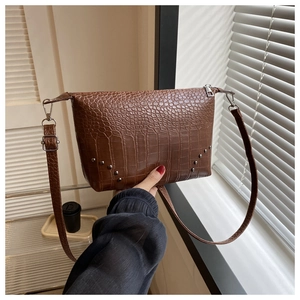 Detail der dunkelbraunen Krokodilledertasche mit Vintage-Metallnieten und Riemen