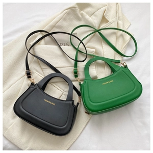 Detail of minimalist black and green handbags with adjustable straps and gold logo