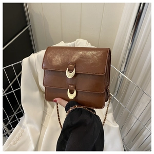 Detail of vintage brown shoulder bag featuring glossy oil wax leather and gold chain