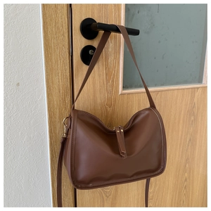 Detailed close-up of brown PU leather tote bag with smooth texture and zipper detail