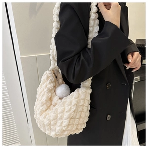 Close-up of white bubble texture shoulder bag with a fluffy pom-pom charm detail
