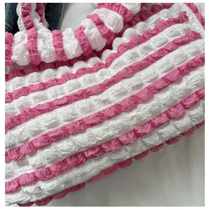 Gros plan sur le tissu seersucker rayé rose et blanc avec texture à bulles du sac