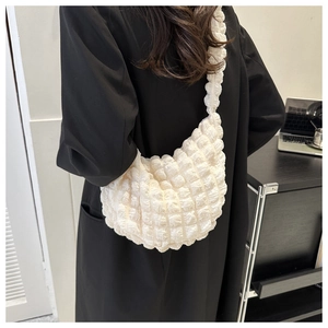 Close-up of white quilted pleated hobo bag texture and wide strap on shoulder