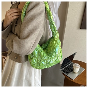 Neon green quilted shoulder bag with iridescent finish shown in a cafe setting