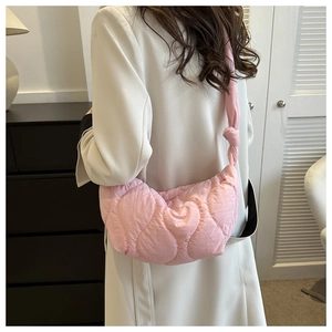 Pink quilted nylon cloud bag with decorative knot detail on shoulder strap in use