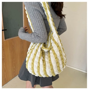 Detail shot of bubble textured yellow and white striped tote bag shown on a shoulder