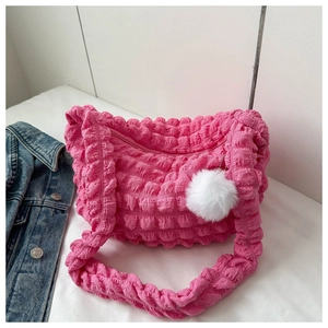 Detail of hot pink popcorn textured shoulder bag with a white fluffy pompom charm