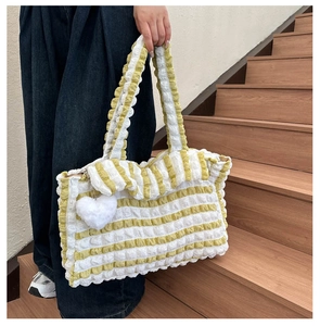 Détail du sac cabas à rayures jaunes et blanches en tissu bulle avec charme de cœur