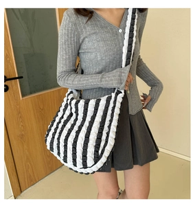 Detail of a large bubble textured black and white checkered tote bag worn by a model