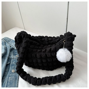 Detail of black popcorn texture fabric shoulder bag with a white fluffy ball pendant