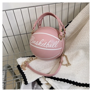 Detail of pink basketball shaped crossbody bag with gold chain and artistic letter print