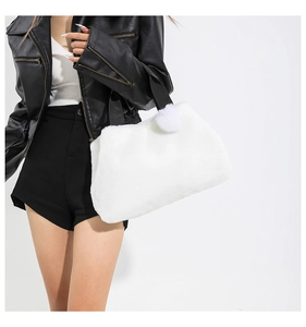 Detailansicht der weißen Plüschtasche mit flauschigem Bommel und schwarzen Trägern