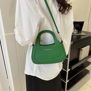 Green leather crossbody bag with white FASHION lettering shown on white shirt model