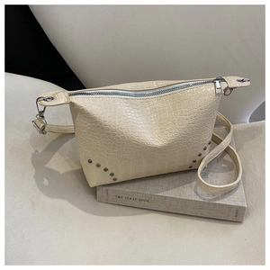 Detail der beige Handtasche mit Krokodilmuster und silbernen Nieten auf einem Buch