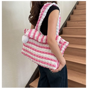 Détail du tissu texturé à bulles rayé rose et blanc sur un grand sac cabas avec pompon