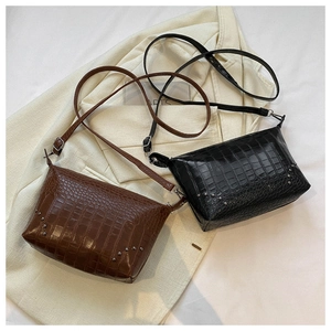 Nahaufnahme der Retro-Krokodilledertaschen mit Metallnieten auf einem weißen Blazer