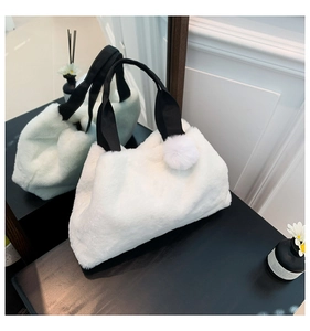 Detail der weißen Plüschhandtasche mit weichem Kunstfell und schwarzen Webgriffen