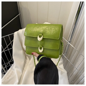 Detailed close-up of green PU leather shoulder bag with gold horseshoe metal buckles