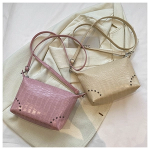 Detail von rosa und beigen Umhängetaschen mit Kroko-Effekt und Silbernieten