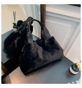 Detail-Spiegelung der schwarzen Plüsch-Handtasche mit flauschigem Bommel-Anhänger