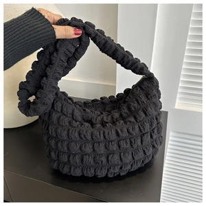 Detail of black cloud-style bubble texture handbag with integrated handle and metal zipper