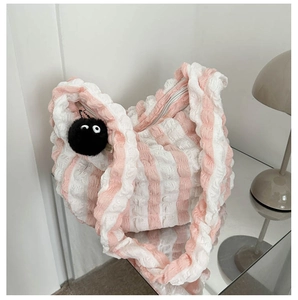 Detail of pink and white textured bubble tote bag with cute black plush charm