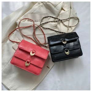 Detail of compact PU leather square bags with dual flaps and gold half-ring hardware