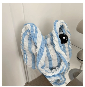 Detail of blue and white striped bubble texture fabric tote bag with plush charm