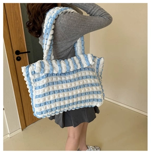 Détail du tissu à bulles rayé bleu et blanc sur un grand sac à bandoulière pour femme