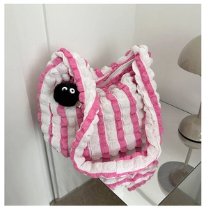 Detail of pink and white striped tote bag with bubble texture and plush soot sprite charm