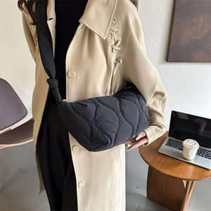 Large black quilted puffer tote bag with wide shoulder strap and knots for daily casual use