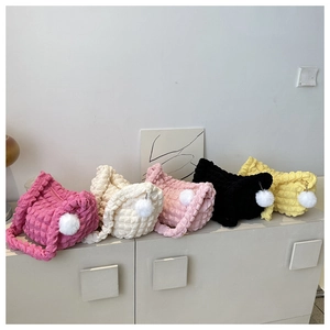 Close-up of pleated shoulder bags in five colors with fluffy white pompom charms
