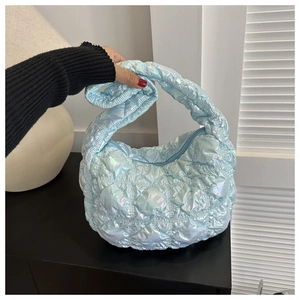 Detailed view of iridescent quilted puffer bag with metallic finish and soft handle
