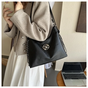 Close-up of black textured large tote bag with metallic logo and chain strap