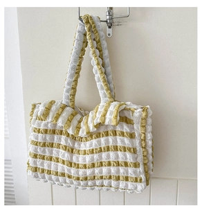 Détail montrant le tissu gaufré et le motif à rayures jaunes et blanches du sac cabas