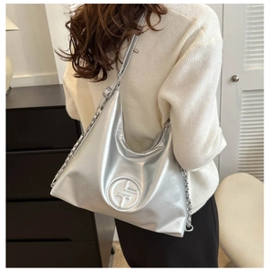 Détail du sac croissant argenté métallisé avec chaîne et logo embossé sur similicuir poli
