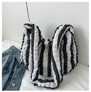 Detail of black and white striped tote bag showing pleated fabric texture and large capacity