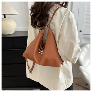Detail of brown soft leather shoulder bag with silver metal buckle on modern background