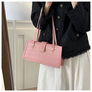Borsa rosa effetto coccodrillo con chiusura dorata indossata con tweed chic