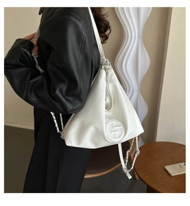Détail du sac triangle blanc avec logo embossé et bandoulière en chaîne argentée