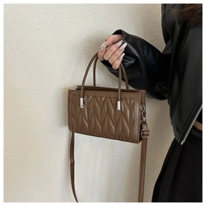 Close-up of brown quilted faux leather bag with V-stitch design and silver metal clasp