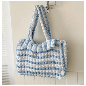 Détail du tissu seersucker rayé bleu et blanc avec texture plissée sur sac fourre-tout