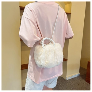 Detail of white plush crossbody bag with woven circular handles on a model