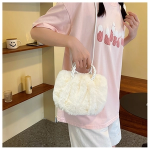 Detailed view of white faux fur plush handbag featuring woven handles and shoulder strap